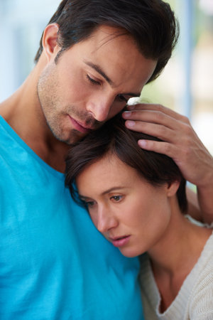Love, sad couple and embrace for support, care or empathy together in serious relationship. Man, woman and comfort partner in marriage for kindness, connection or console for grief with trust in homeの写真素材