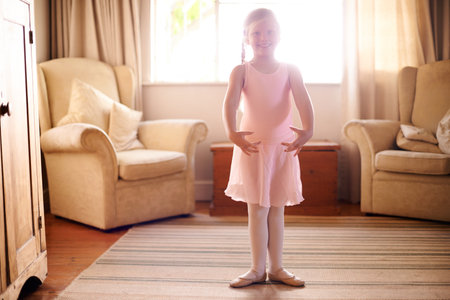 Girl, portrait and ballet tutu for dance, confidence and skill in living room for growth or fun in home. Child, artist and smile with dancer, practice or development for creative in house loungeの写真素材