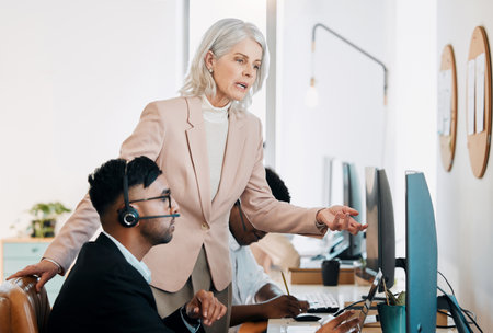 Woman, man and training by computer in call center with review, feedback or support at telemarketing agency. Mature manager, people and teaching for mentorship with agent, pc and advice at help deskの写真素材