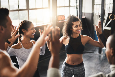 High five, happy and people in gym for exercise, training and workout target, teamwork and goals. Sport, friends and men with women celebrate with gesture for fitness, health and performance in classの写真素材