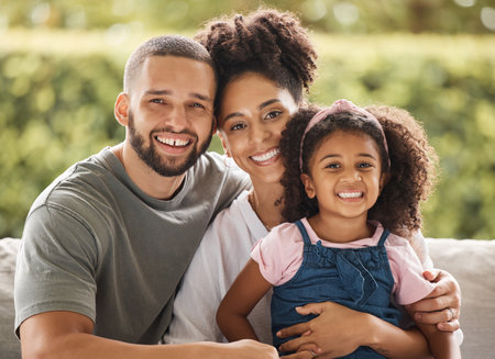 Happy family, mother and father with their child love being home for bonding, quality time and relaxing together. Smile, mom and dad enjoy hugging and connecting with their young girl on the weekendの写真素材