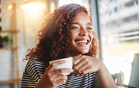 Happy woman, laughing or morning with coffee at cafe for caffeine, funny joke or beverage. Face, female person or customer with smile for comedy, fun hospitality service or humor at indoor restaurantの写真素材