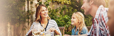 Mom, dad and children at patio lunch with smile, bonding and family eating together in backyard. Father, mother and kids at table for outdoor garden picnic with food, laughing and love on banner.の写真素材