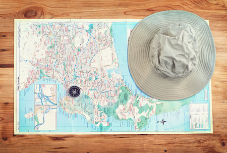 Hat, map and above with compass on table for itinerary schedule, adventure explore and direction....