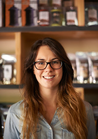 Portrait, barista and happy woman with glasses in cafe, small business and welcome in hospitality industry. Owner, face and entrepreneur in coffee shop, startup and franchise for service in Spainの写真素材