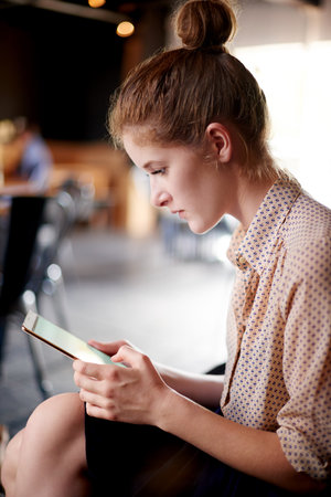 Tablet, typing and woman in coffee shop with research for travel tips for digital nomad. Reading, content creation and female influencer with creative blog for online cafe review on technology.の写真素材