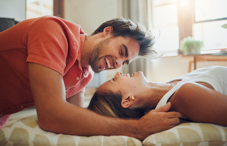 Love, laugh and happy couple on floor in home for connection, bonding or relax with partner on cushions. Living room, man and woman with funny joke, comedy and communication for relationship togetherの写真素材