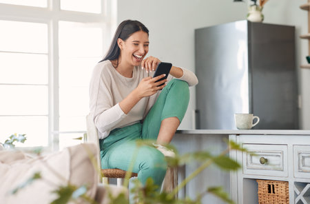 Woman, laughing and relax with phone in kitchen with funny dating site, communication or fun networking. Girl, smartphone and happy in home for text message joke, social media or internet browsingの写真素材