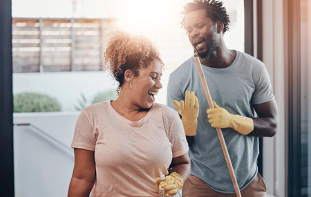 Couple, happy and singing in home with cleaning, bonding or fun with chores on weekend. Man, woman or karaoke music in living room with dance, apartment hygiene or help appreciation with housekeepingの写真素材