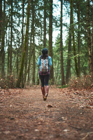 Back, woman and walking in forest for travel, adventure and journey in winter fashion. Person,...