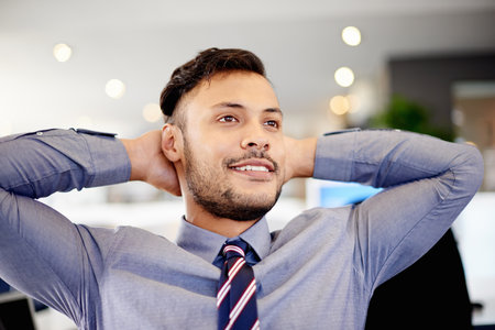 Rest, happy and businessman in office with finished financial report with company revenue. Relax, achievement and male finance advisor with hands behind head for completed investment in workplace.の写真素材