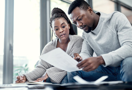 Home, black couple and serious with paperwork on sofa for finance plan or interest rate on loan application. Apartment, people and reading with documents on couch for bank statement and credit scoreの写真素材