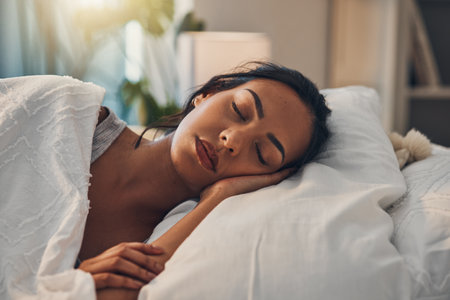Woman, tired and sleeping in bed for rest, comfort and exhausted in home with blanket and pillow. Female person, fatigue and asleep in bedroom for nap, dream and burnout with relax, peace and breakの写真素材