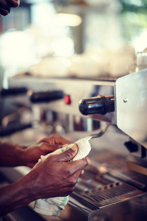 Man, hands and cleaning coffee machine in shop, closeup and wiping for health and safety policy. Compliance, hygiene and professional in restaurant for sanitation, disinfect steel and bistro workの写真素材