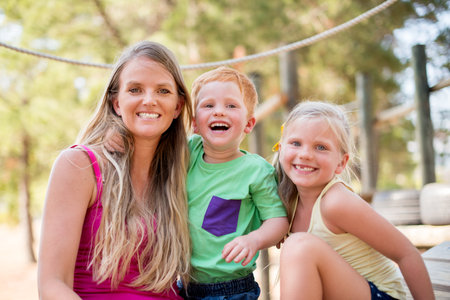 Mother, children and outdoor portrait for hug, explore nature and playground for laughing together. Mommy, kids and support with family bonding for happiness, park embrace and fantasy adventure gamesの写真素材