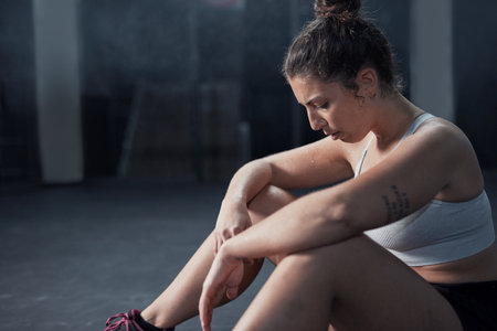 Tired, woman and relax for fitness at gym from sports workout, exercise burnout and training performance. Fatigue, female person and rest with break, breathing and physical recovery of wellness goalsの写真素材