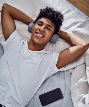 Portrait, relax and happy man listening to music on headphones, audio or sound subscription in home. Face, bedroom and person streaming radio, hip hop playlist or rock song with technology in Brazilの写真素材