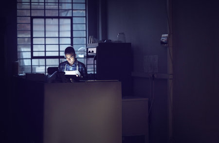 Small business, dark and man in coffee shop, tablet and apron with typing, connection and startup. Person, entrepreneur and barista with tech, evening and communication with digital app and nightの写真素材