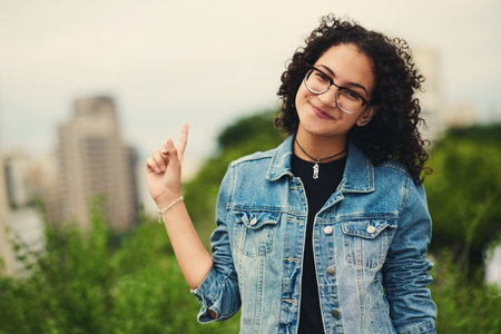 Outdoor, woman and happy on portrait with pointing in city background at park to relax and break Mexico. Female person, teenager and smile or satisfied with confidence for adventure, fun and chillの写真素材