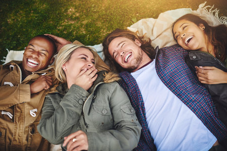 Friends, picnic and above of people in nature on grass with smile on holiday, vacation and adventure outdoors. Travel, happy and men and women with blanket for bonding, relax and fun on weekendの写真素材