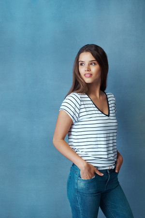 Thinking, woman and confidence in studio for fashion, casual style and cotton material with clothes. Space, female person and model with smile for inspiration, hipster and pride by blue backgroundの写真素材