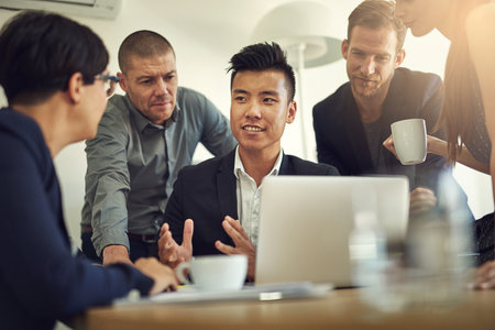 Office, discussion and group with laptop, planning and collaboration for project, ideas and confident. Brainstorming, talking and corporate people in meeting, online and actuary for insurance companyの写真素材