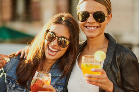 Hug, friends and girls with alcohol, fun and bonding for summer break in university and outdoor. Party, happy and people with shades, reunion and celebration for birthday, embrace or drinks for womenの写真素材