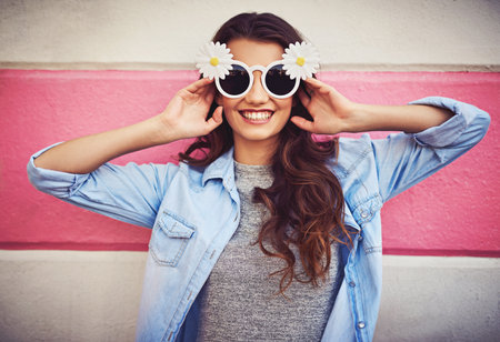 Fashion, smile and sunglasses with woman on wall background for summer or trendy style in color. Happy, shades and urban with confident model person in denim jacket for casual clothes wardrobeの写真素材