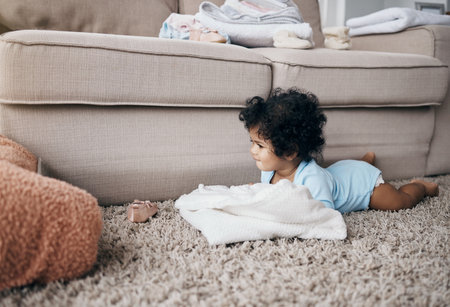 Baby, home and tablet for streaming cartoon, child development and tummy time on floor of lounge. Infant, girl and online entertainment for watching animation, internet and playing with cozy blanketの写真素材