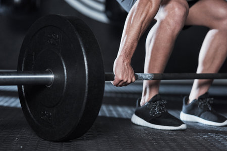 Gym, hands and person with barbell for training, stability and balance with workout for muscle strength. Exercise, legs and bodybuilder with weightlifting for wellness, growth challenge and fitnessの写真素材