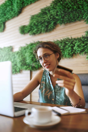 Cafe, happy and businesswoman with laptop for credit card, digital banking and transaction for payment. Restaurant, customer and technology with debit for online shopping, reading info and ecommerceの写真素材