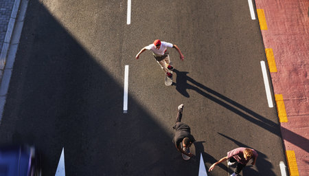 Active, skating and friends with skateboard, group and race on road in city, fitness and high angle. Outdoor, above and travel for competition on street, skateboarding and practice for game or peopleの写真素材