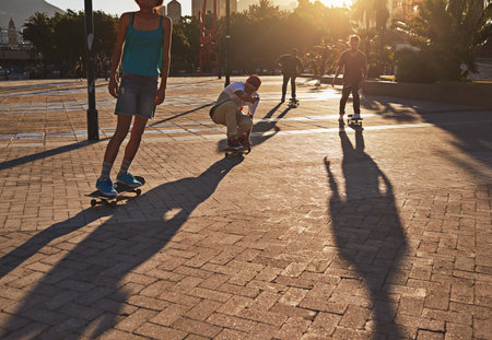 Friends, skateboard people and sunset in street, city or outdoors for fun practice. Exercise, fitness and group sports with training and skaters bonding together on urban road for downtown workoutの写真素材