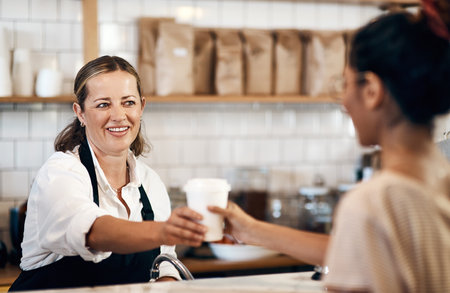 Coffee shop, giving and waitress with customer for drink, caffeine beverage and cappuccino in cafe. Small business, espresso and woman with barista for service buying in restaurant, store and dinerの写真素材