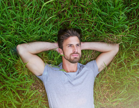 Thinking, relax and top view of man on grass for peace, calm and reflection on holiday. Dream, male person and lying on lawn above for resting, planning future and decision outdoor on hiking breakの写真素材