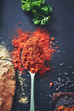 Table, spoon and cayenne pepper spice for cooking, flavor and ingredients for dinner food. Cuisine, tableware and collection of organic ground chilli, texture and culinary condiments in kitchen.の写真素材