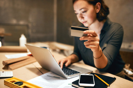 Credit card carpenter and woman in workshop, laptop and online shopping with payment for supplies....