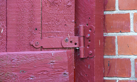 Closeup, red door and hinge with rusty metal for old exterior, damage or vintage doorframe of...
