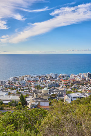 Above, beach and city with vacation, coastline and adventure with environment. Empty, blue sky or seaside with buildings, travel or journey with holiday, wallpaper or earth day for ocean conservationの写真素材