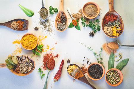Spices, ingredients and selection of organic seasoning on studio background for cooking and top view. Utensils, herbs condiments or flavor additives with curry leaves, masala powder and ground pepperの写真素材