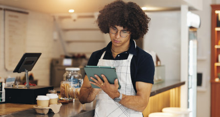 Waiter, tablet and search with man in cafe for inventory checklist, barista and hospitality. Customer review, restaurant menu and reading with person in coffee shop for sales, stock and price checkの写真素材