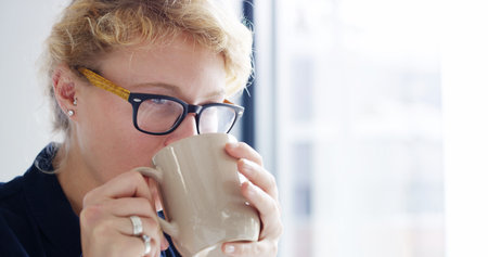 Thinking, writer and woman with coffee, office and inspiration for story in creative agency or planning. Contemplating, editor and thoughtful for project on break, person and drinking tea in businessの写真素材