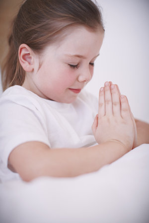 Home, child and girl with prayer for worship, gratitude or communication with God before bedtime. House, Christian and kid with hands for praise, religion or faith for spiritual connection with Jesusの写真素材