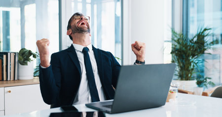 Excited, businessman and laptop with fist pump in celebration for good news or promotion at office. Happy man, accountant or investor with computer for winning, deal or financial profit on investmentの写真素材