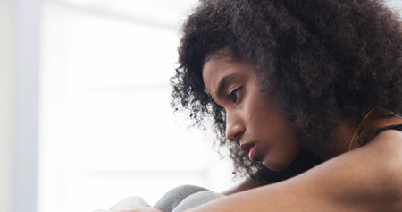 Sad, thinking and girl with depression at house of loneliness, remember past or trauma challenges. African, person and anxiety from stress flashback, mourning loss and self doubt with grief of memoryの写真素材