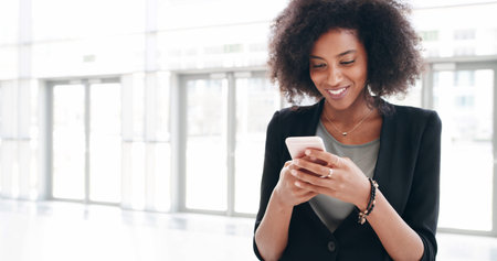 Business woman, phone and texting in office lobby with social media, email or convention networking. Communication, internet and consultant with cellphone, mobile app and chat online for conferenceの写真素材