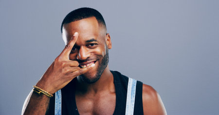Rocker, hand and smile with portrait of black man in studio for metal music, punk identity and crazy. Devil horn sign, edgy or attitude with person on background space for energy, emoji or expressionの写真素材