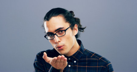 Blowing, kiss and portrait of man in studio with reaction for flirting, romance and pride. Mockup space, hand gesture and person with emoji for love, dating and valentines day on gray backgroundの写真素材