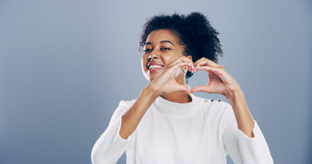 African student, portrait and heart hands with love emoji, gesture and support on grey background space in studio. Woman, smile and sign or shape, symbol and kindness for valentines day date mockupの写真素材