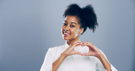 Student, portrait and heart hands with love emoji, gesture and support on grey background space in studio. African woman, smile and sign or shape, symbol and kindness for valentines day date mockupの写真素材